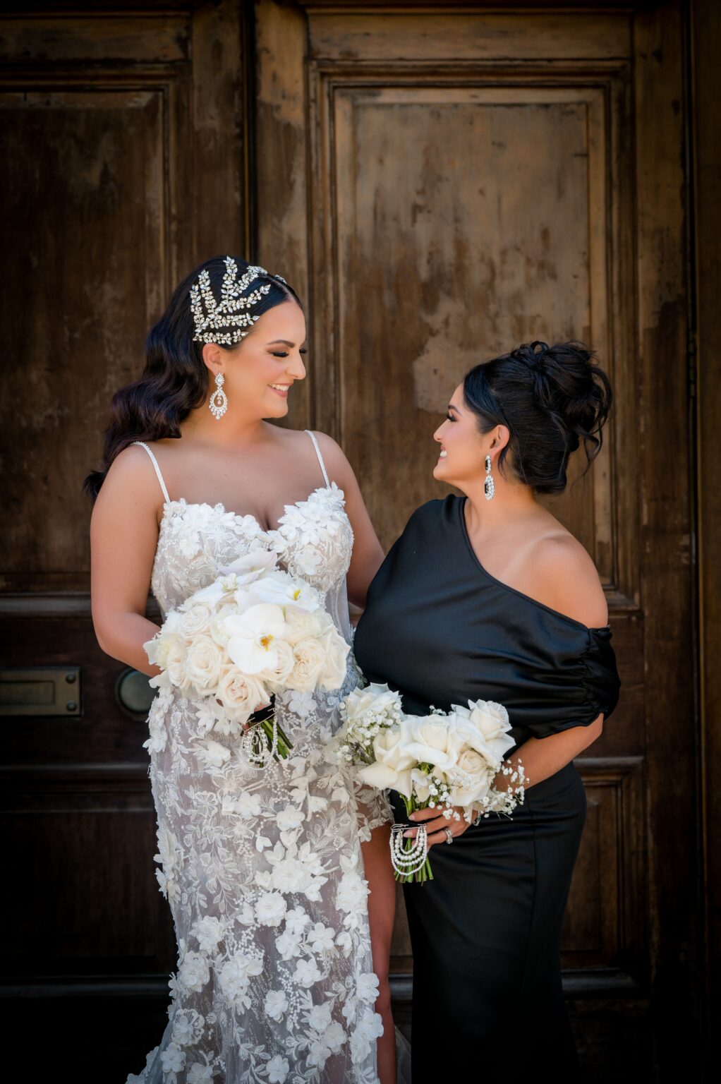 Two women standing next to each other holding flowers.