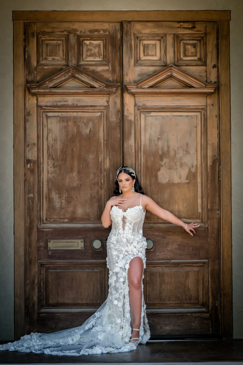 A woman in white dress standing next to brown door.