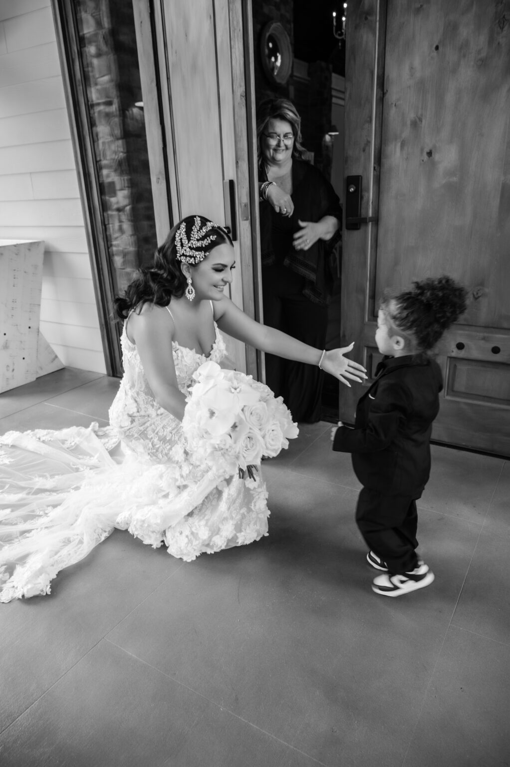 A woman in a white dress holding the hand of a young boy.