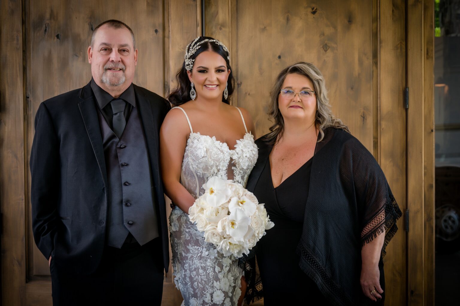 A bride and her parents posing for a picture.