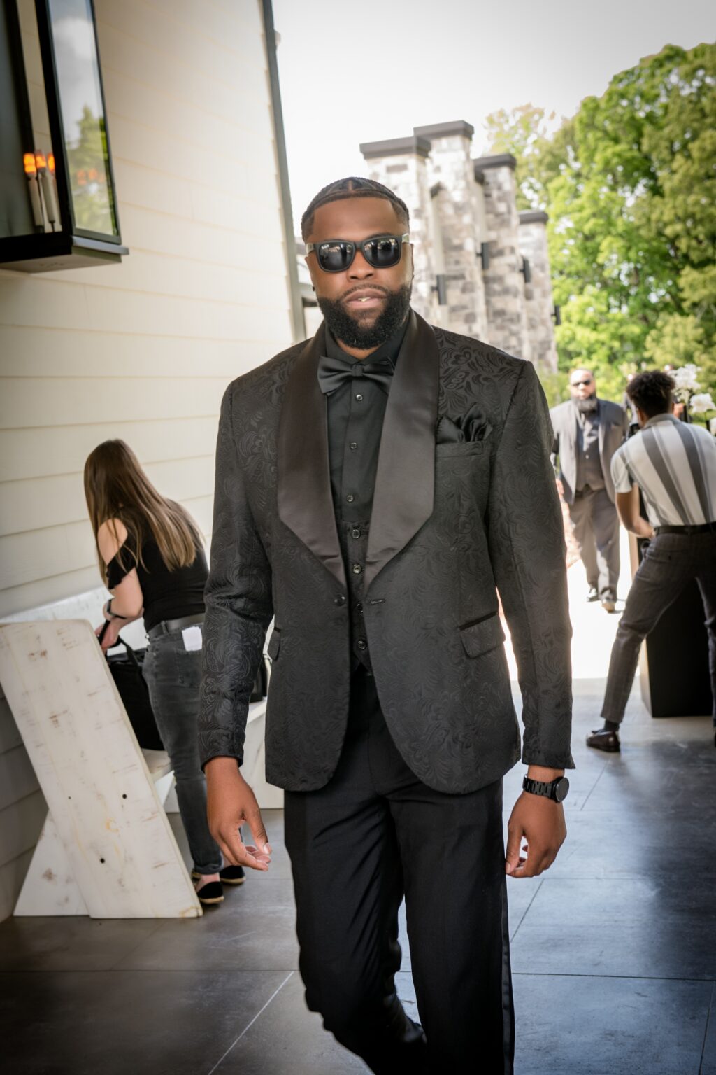 A man in a suit and sunglasses standing on the street.