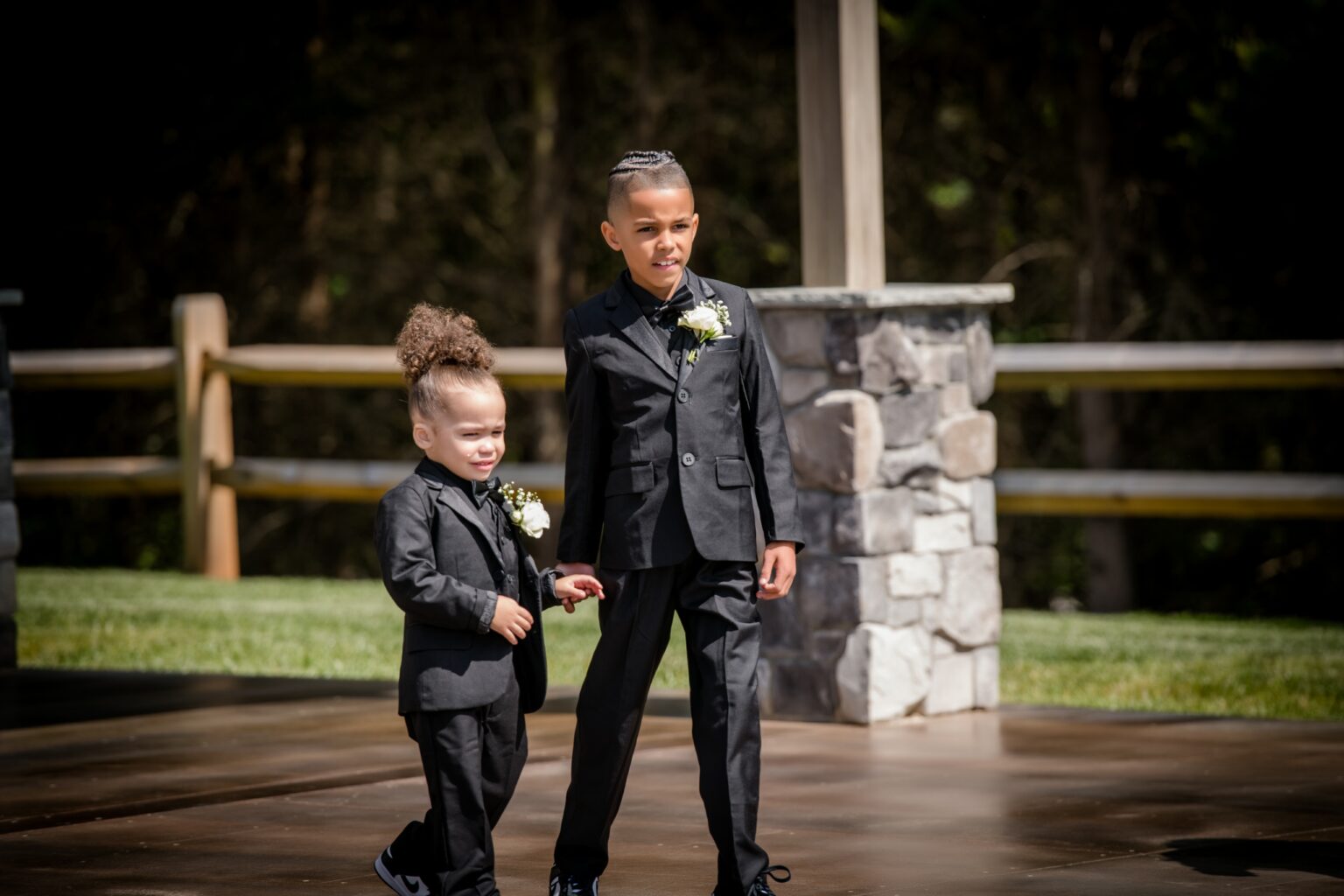 Two young boys in suits holding hands.