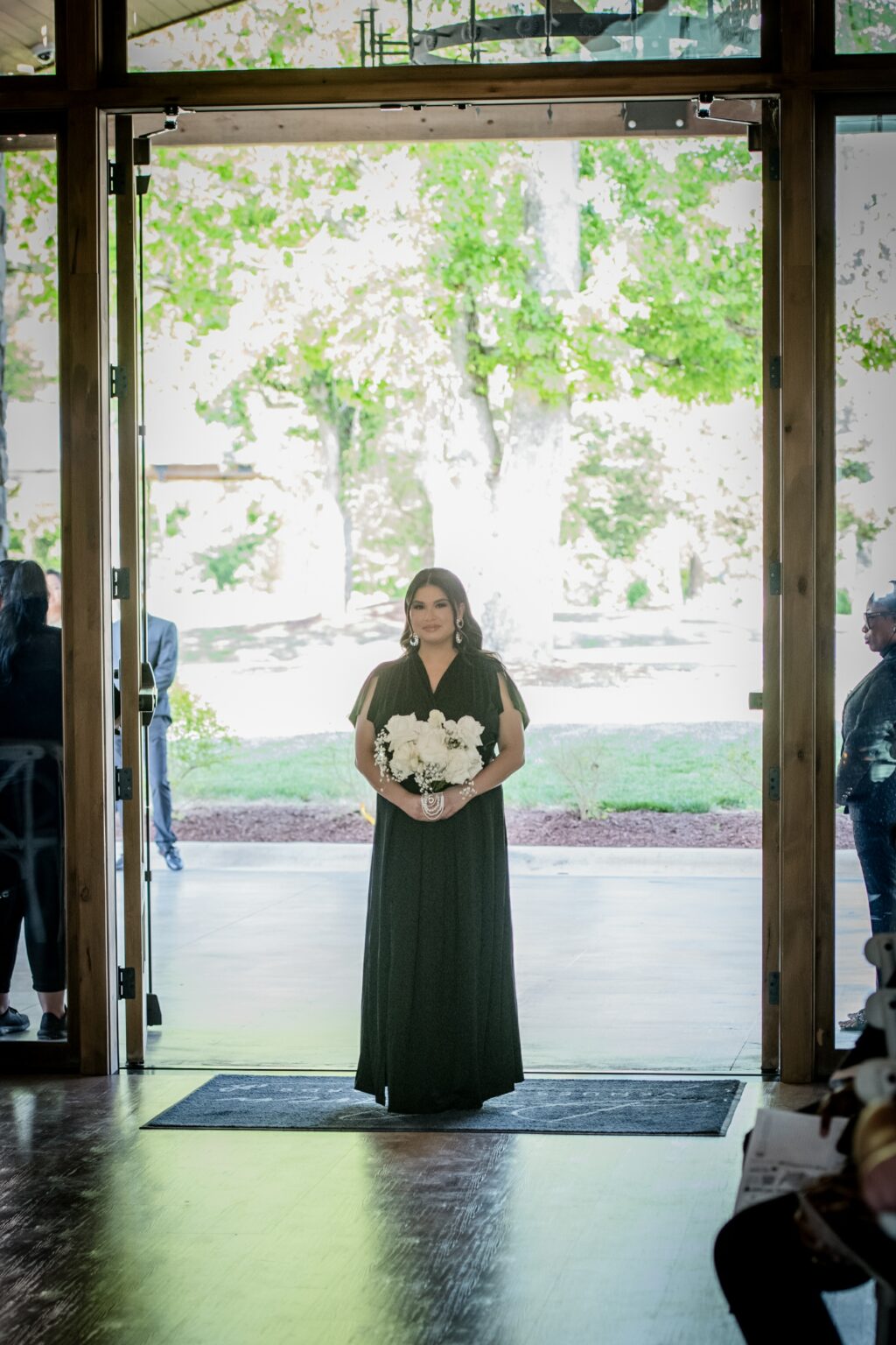 A woman standing in front of a door holding flowers.