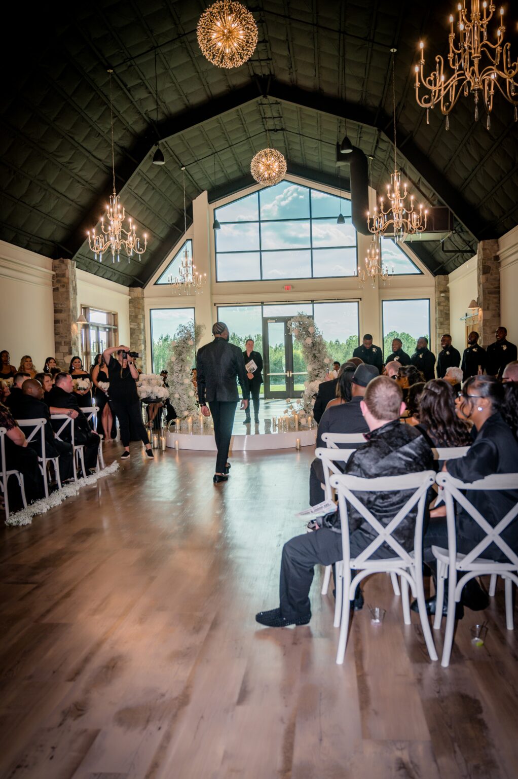 A man walking down the aisle of an indoor wedding.