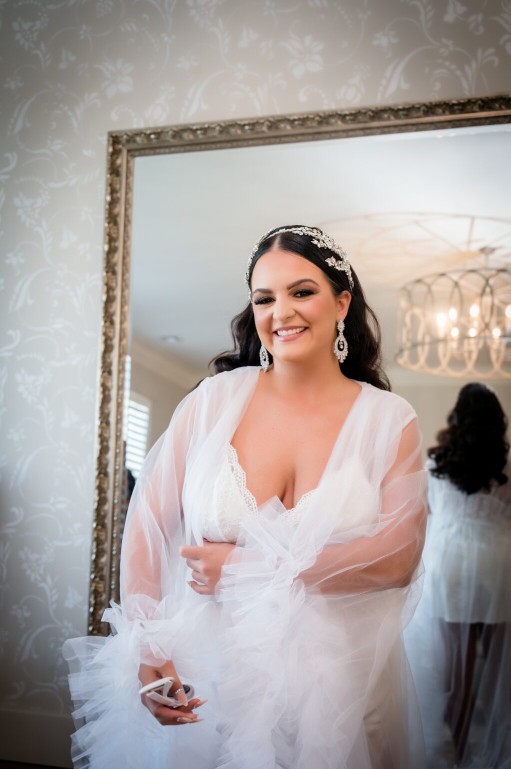 A woman in white dress standing next to a mirror.