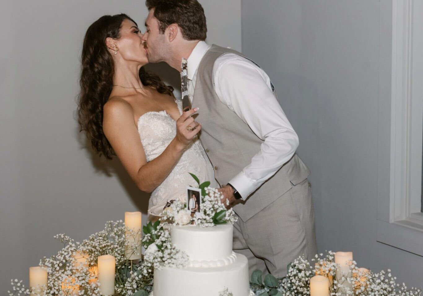 A bride and groom kissing in front of a wedding cake.