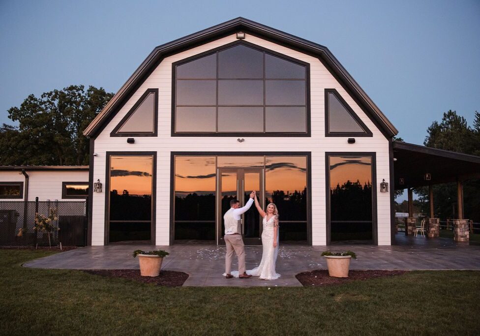 A bride and groom standing in front of their wedding venue.
